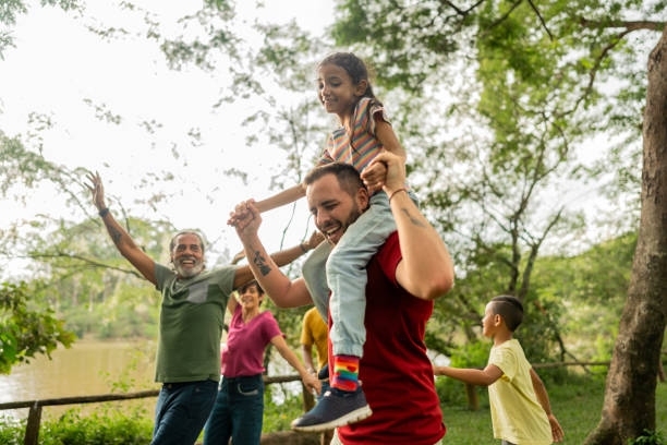 step father having fun during piggyback with adopted daughter on a public park