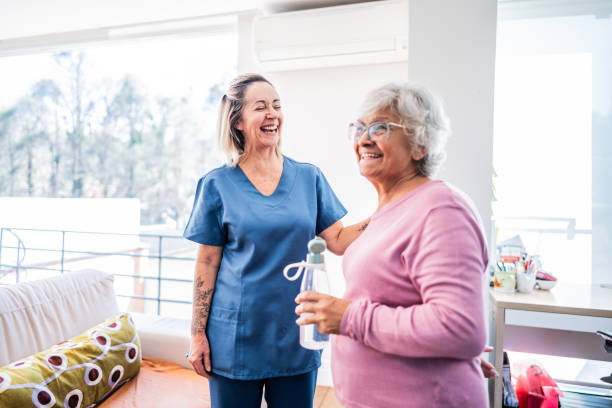 happy senior woman and physical therapist at home